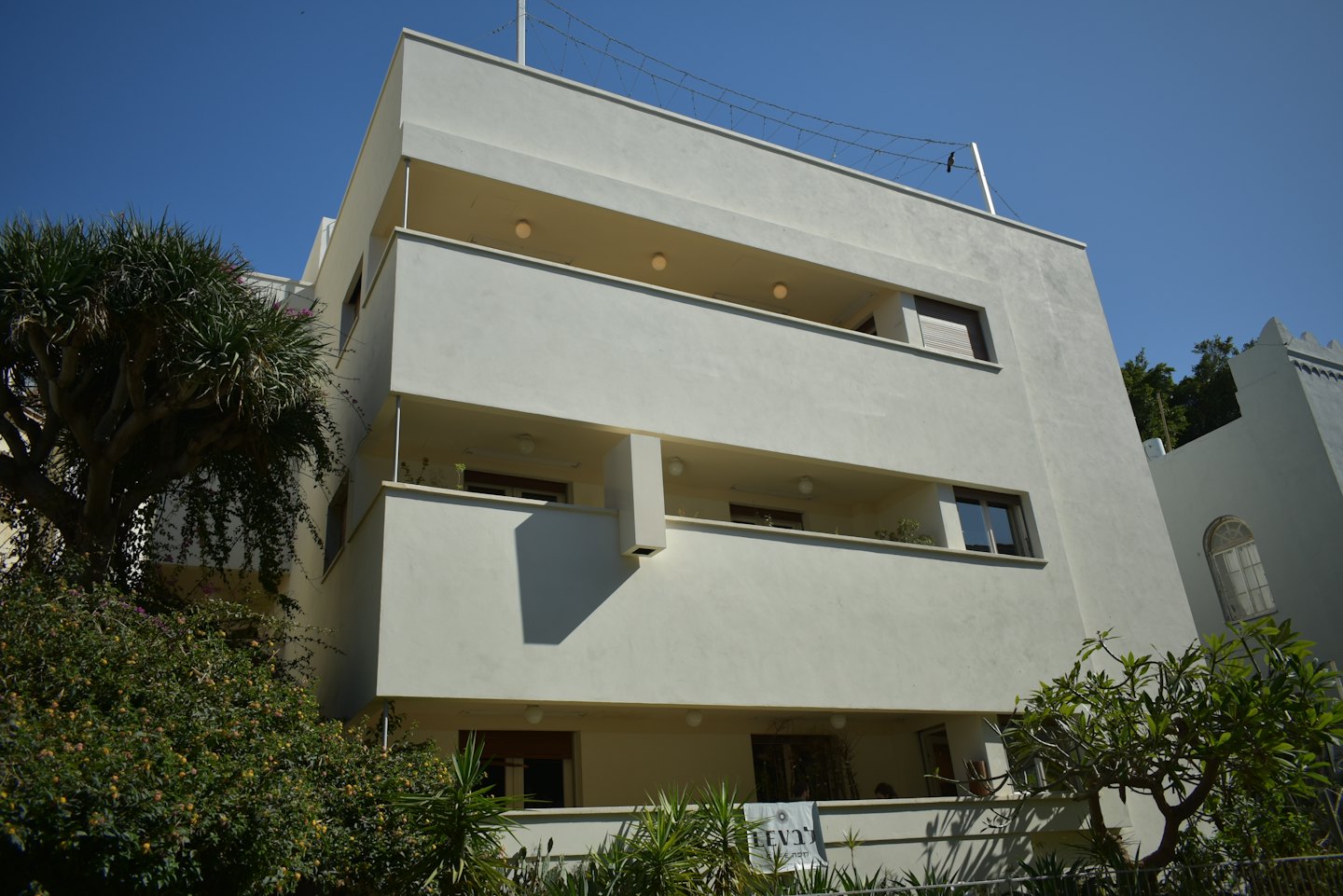 Modernistisches Apartmenthaus mit gestaffelten Balkonen und üppigem Grün.