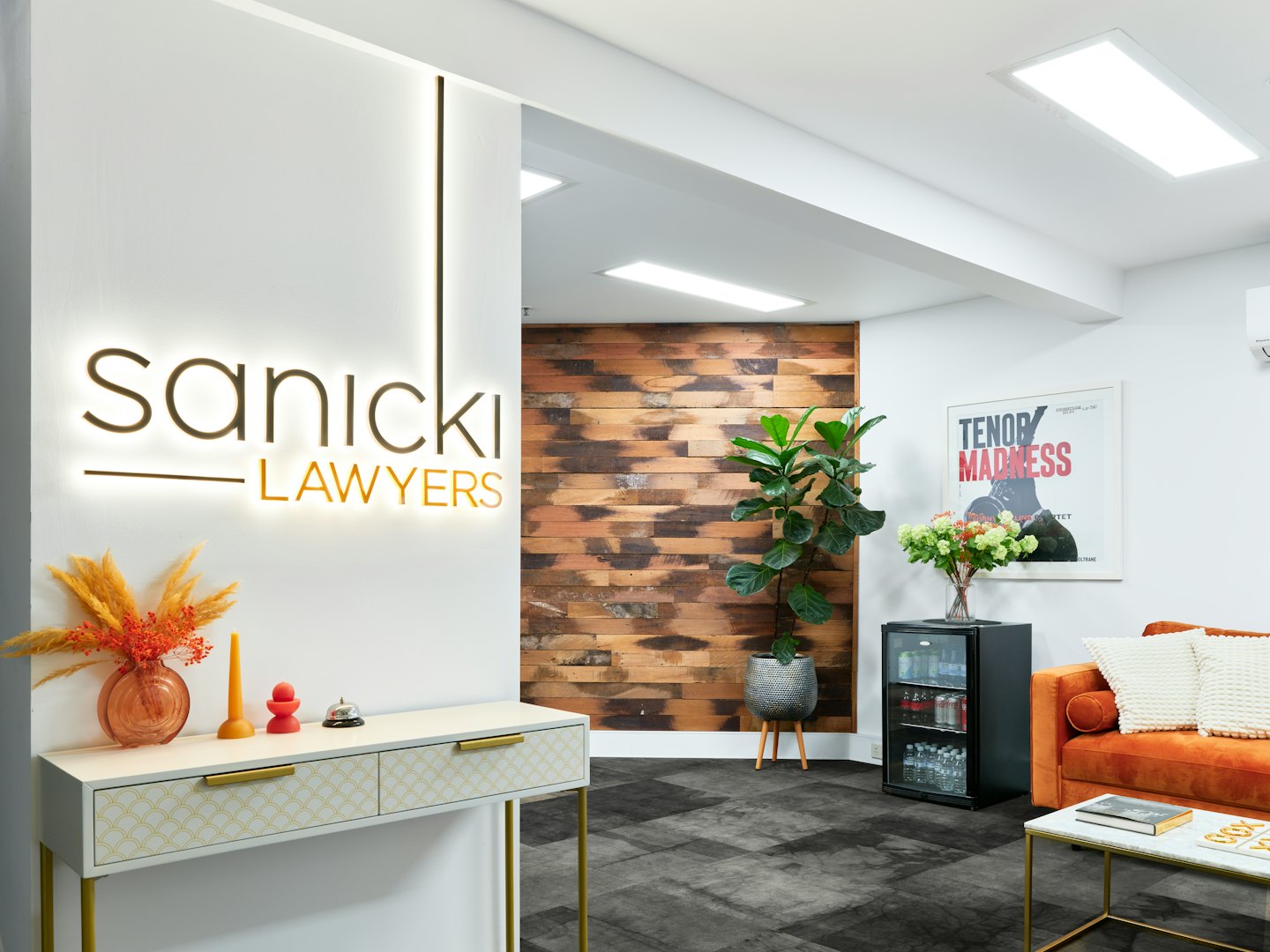 Moderne Bürorezeption mit Sofa und Sanicki Lawyers Schild.
