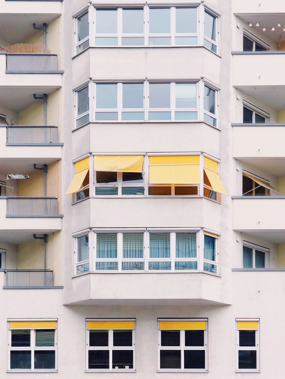 Modernes Wohnhaus mit weißer Fassade und gelben Markisen.